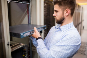 Technician removing server from rack mounted server in server room